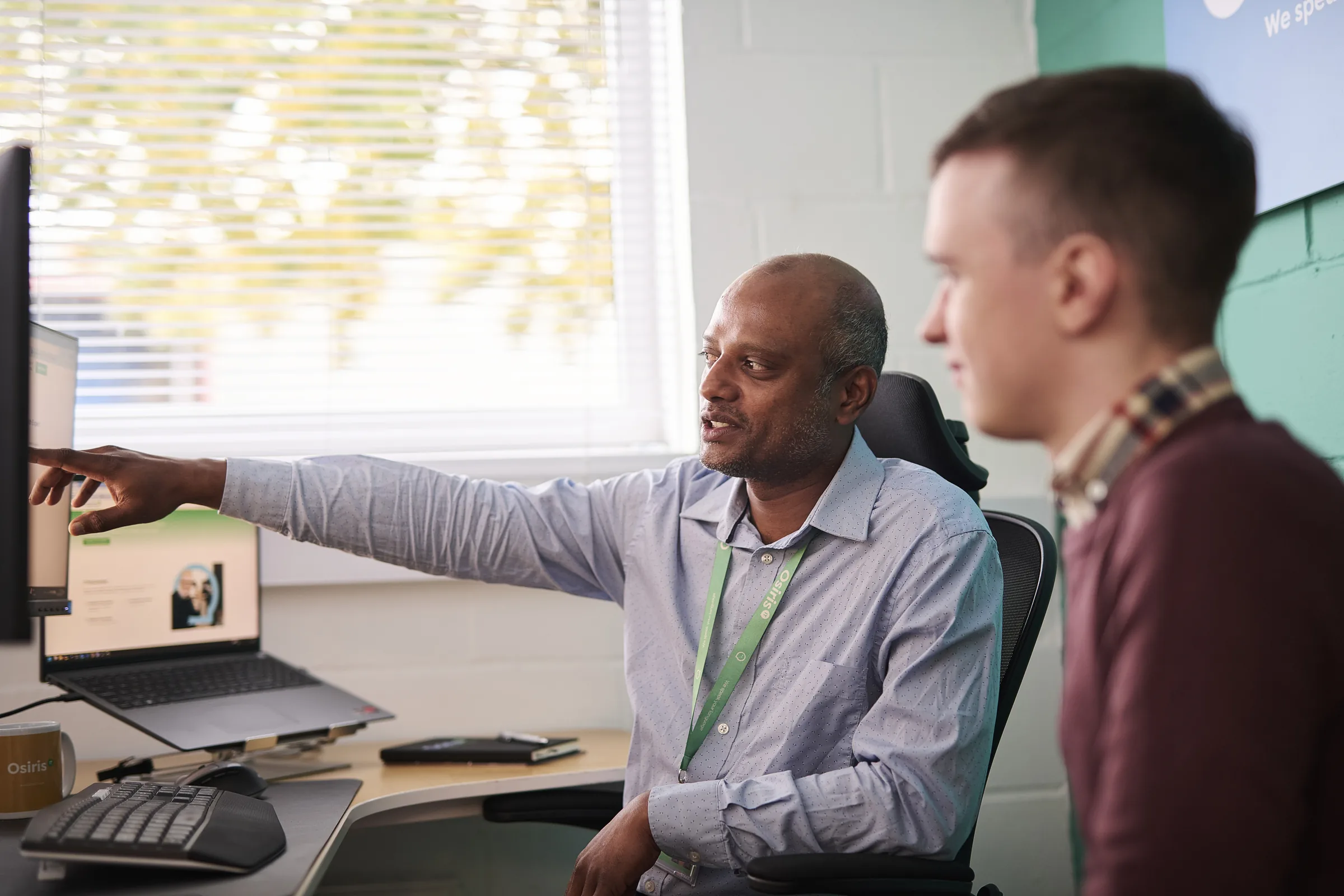 Osiris consultants discussing a practical technology plan around a laptop.