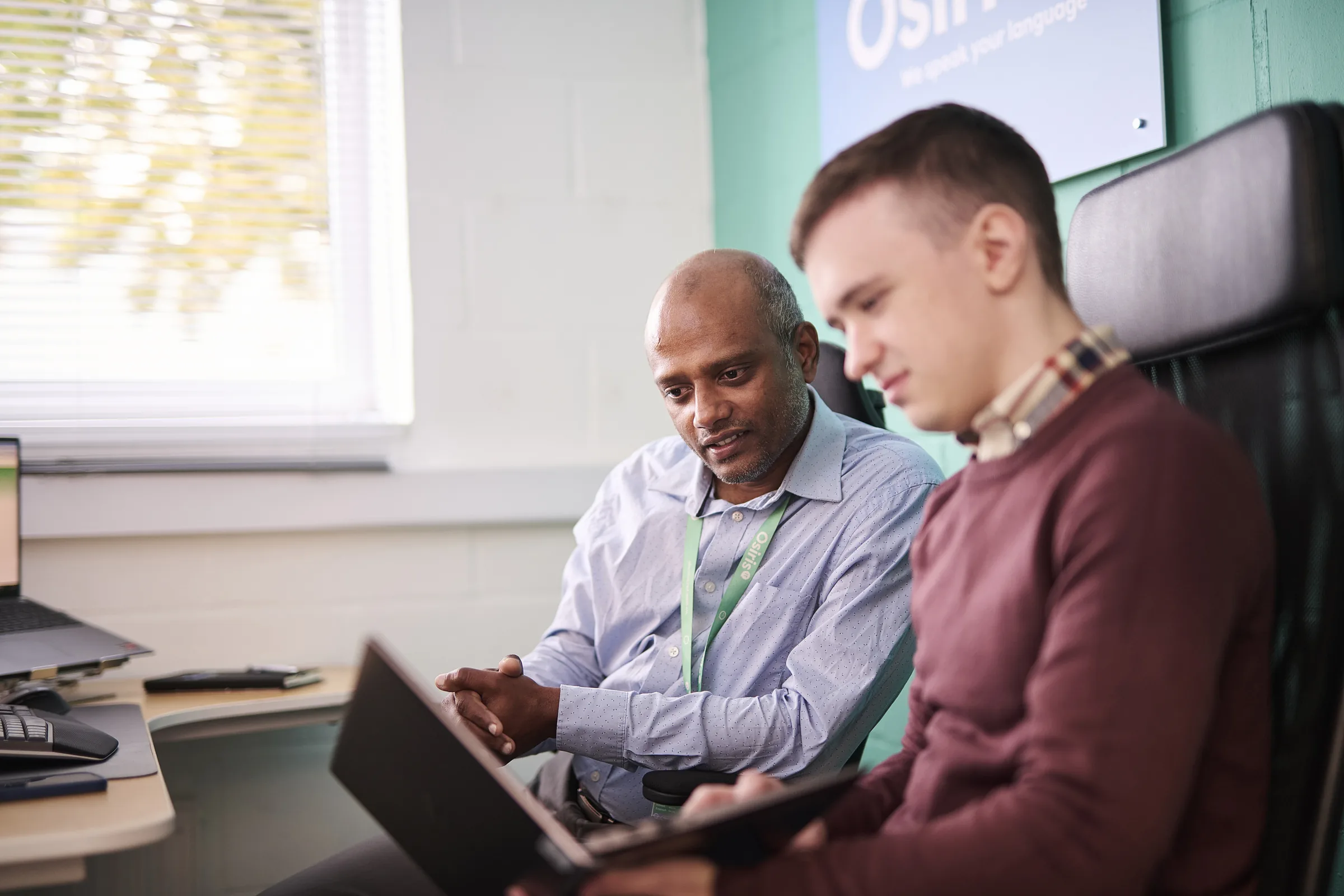 Senior Osiris consultant reviewing procurement priorities with a client at a laptop.