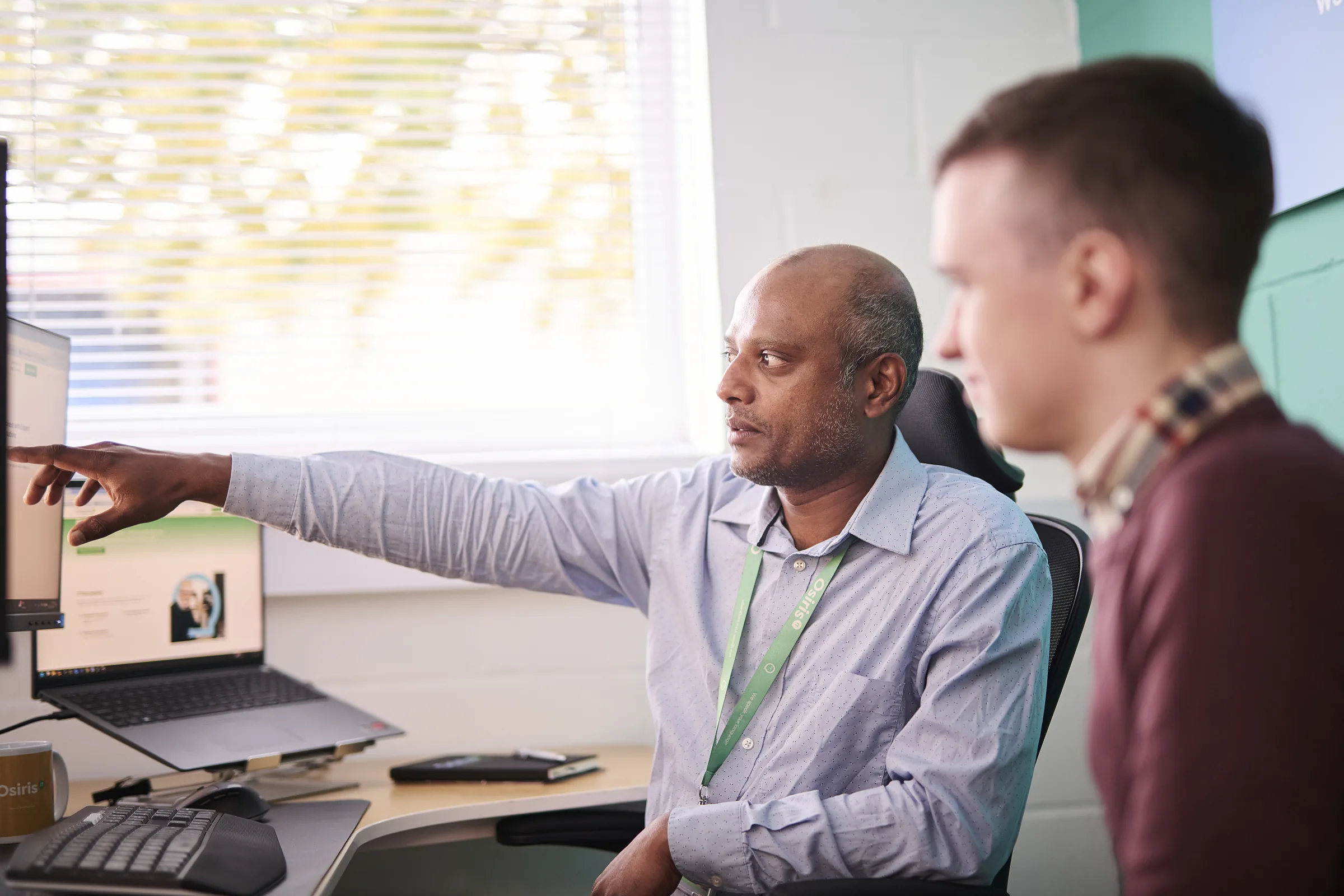 Osiris consultants discussing a practical technology plan around a laptop.